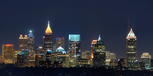 Atlanta skyline at night featuring illuminated skyscrapers, including Bank of America Plaza and nearby towers.